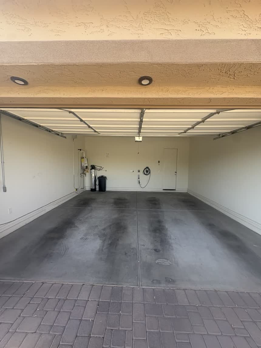 Bare grey concrete garage floor with tyre marks and oil staining before coating